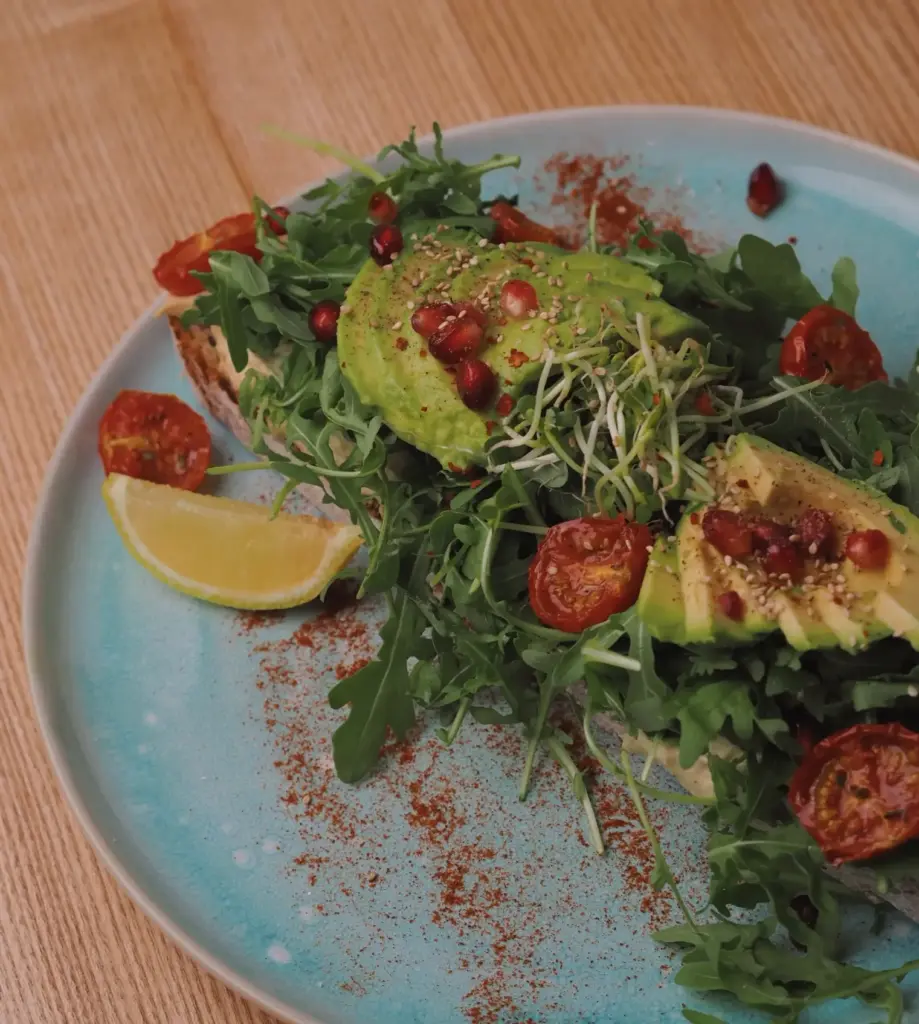Avocadobrot mit Sauerteigbrot, Hummus, Rucola, Avocado, Kirschtomaten, Sprossen & Granatapfel