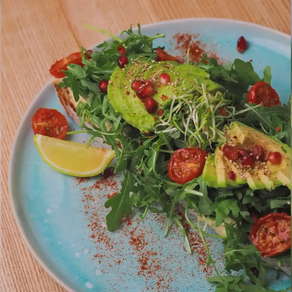 Avocadobrot mit Sauerteigbrot, Hummus, Rucola, Avocado, Kirschtomaten, Sprossen & Granatapfel